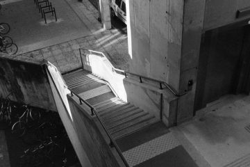 Black and white urban scene with concrete staircase and bicycles in Compiègne, France.